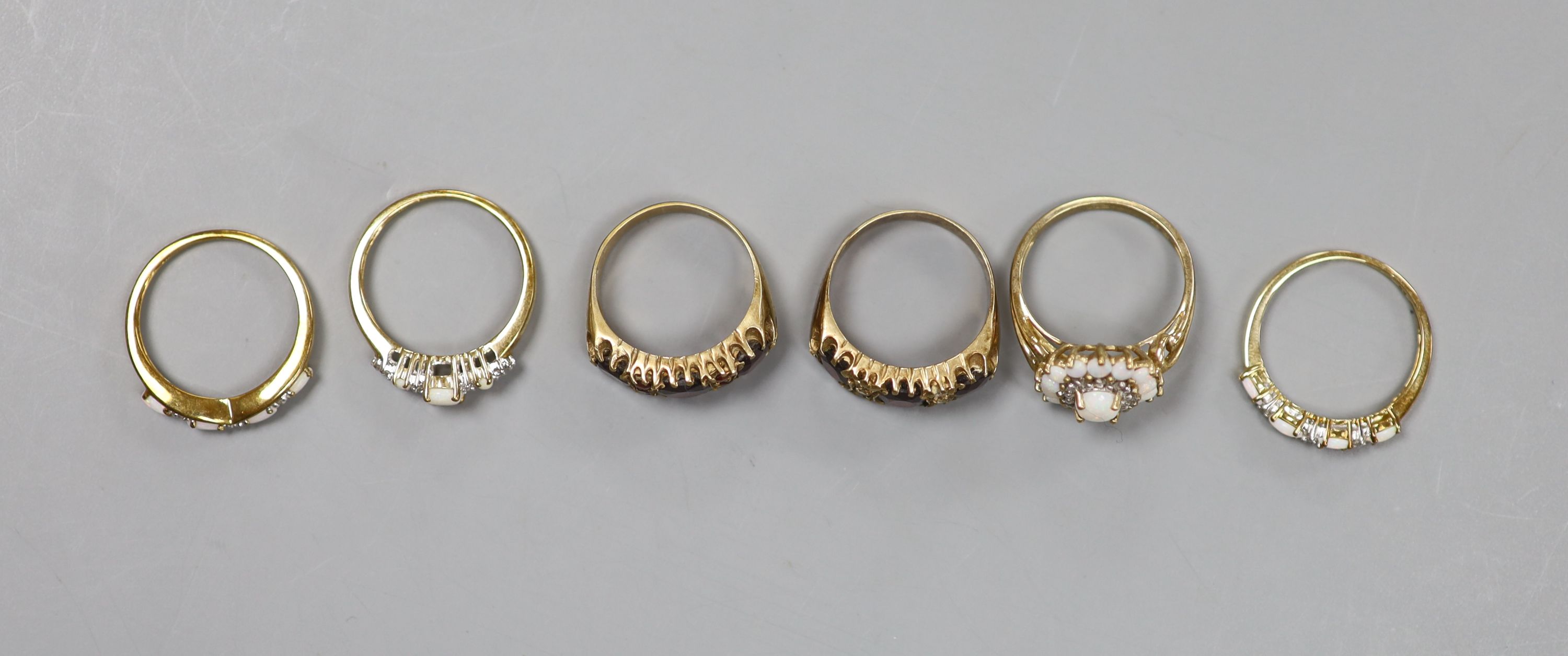 A suite of three opal and 9ct gold rings and three other 9ct gold gem-set rings